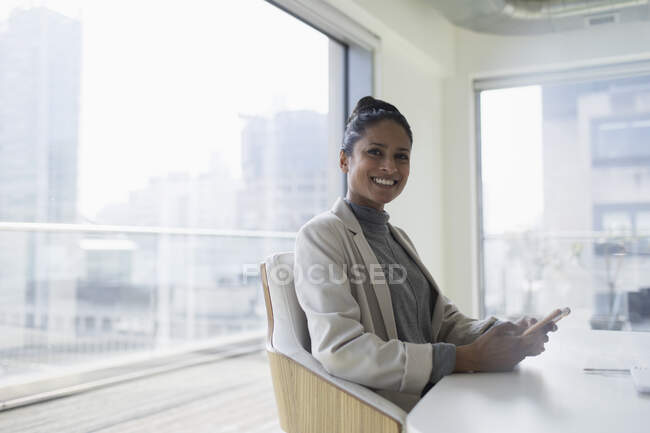Retrato feliz, mulher de negócios confiante com telefone inteligente na sala de conferências — Fotografia de Stock