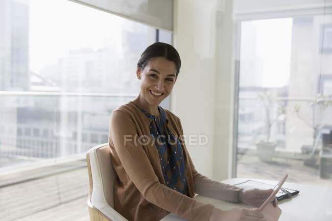 Portrait happy, confident businesswoman using digital tablet in conference room — Stock Photo