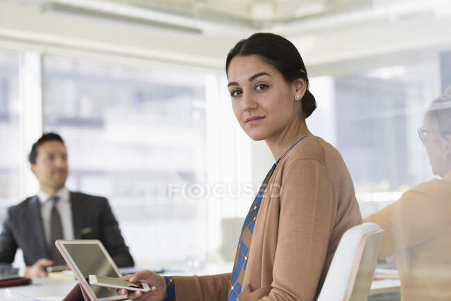 Retrato mujer de negocios confiada con teléfono inteligente en la reunión de la sala de conferencias - foto de stock