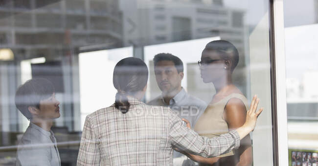 Les gens d'affaires parlent à la fenêtre ensoleillée du bureau urbain — Photo de stock