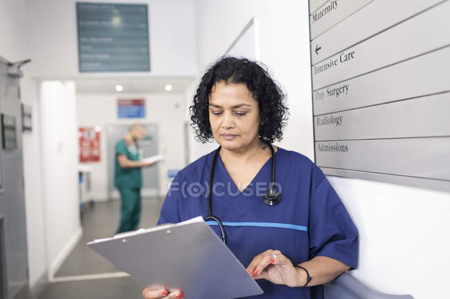 Médica com ficha médica a fazer rondas no corredor hospitalar — Fotografia de Stock