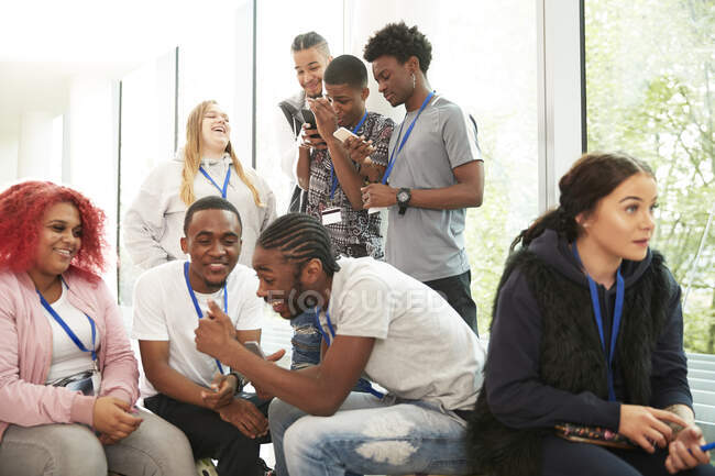 Estudiantes universitarios usando teléfonos inteligentes y pasando el rato - foto de stock