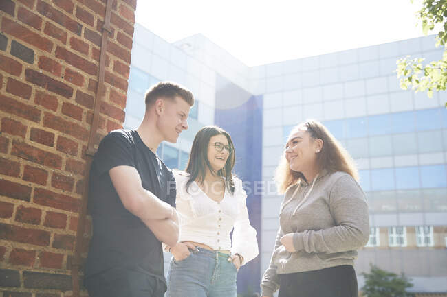 Estudantes universitários conversando fora do edifício ensolarado — Fotografia de Stock