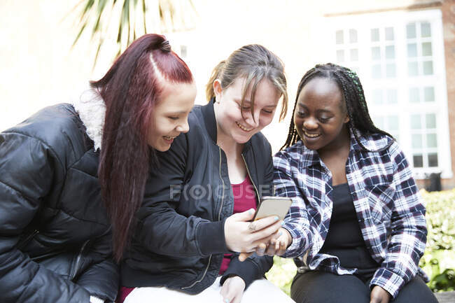 Amigos jóvenes que utilizan teléfonos inteligentes - foto de stock