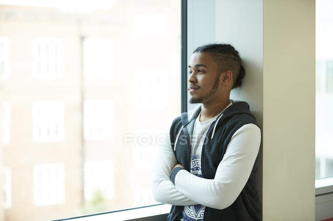 Miúdo adolescente atencioso olhando pela janela — Fotografia de Stock