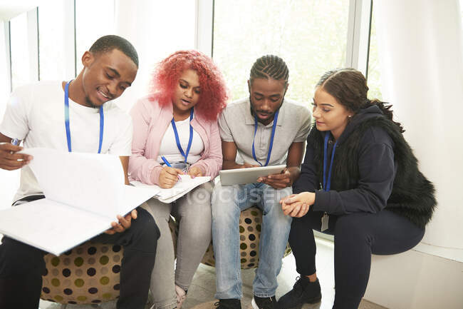 Estudiantes universitarios con cuadernos y tableta digital estudiando - foto de stock