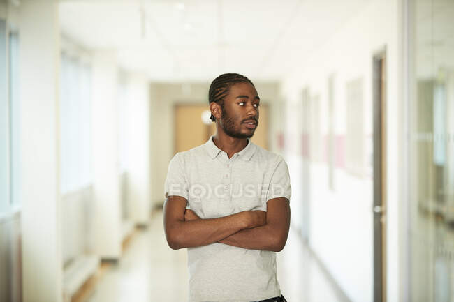 Retrato jovem confiante com braços cruzados no corredor — Fotografia de Stock