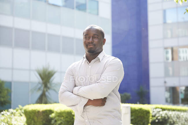 Portrait confident young man with arms crossed outside sunny building — Stock Photo