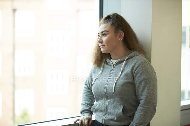 Ragazza adolescente riflessivo guardando fuori dalla finestra — Foto stock