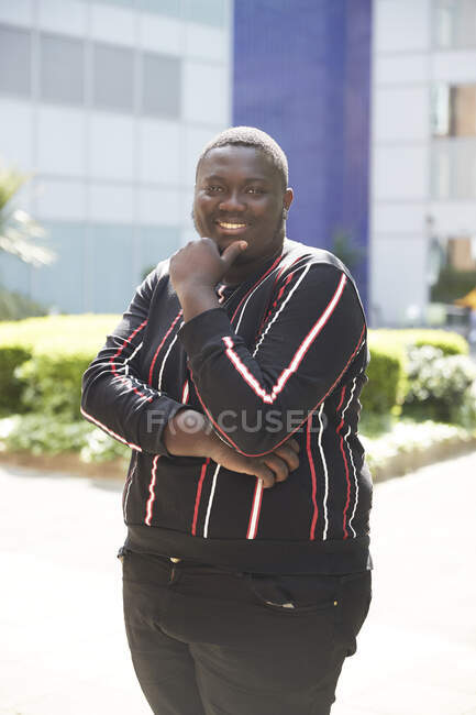 Portrait confident young man standing outside sunny building — Stock Photo