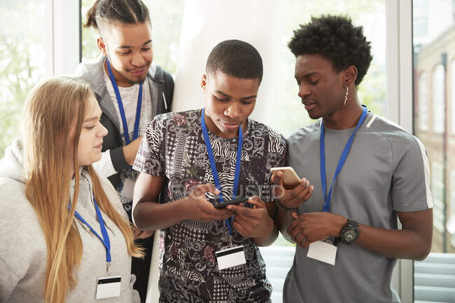 Estudiantes de secundaria con teléfonos inteligentes pasando el rato - foto de stock