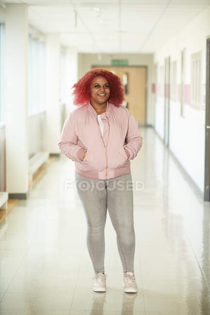 Portrait confident teenage girl in high school corridor — Stock Photo