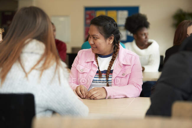 Young female college student listening to classmate in classroom — Stock Photo