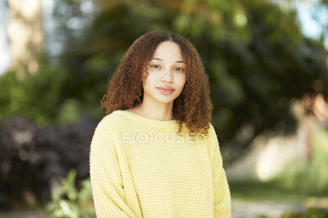Portrait confident young woman in yellow sweater — Stock Photo