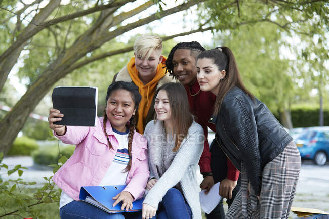Estudiantes universitarios felices tomando selfie con tableta digital en el parque - foto de stock