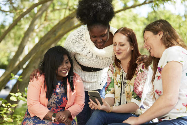 Female friends using smart phone in park — Stock Photo
