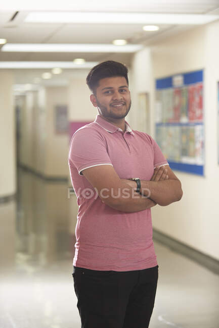 Retrato confiado joven estudiante universitario masculino en corredor - foto de stock