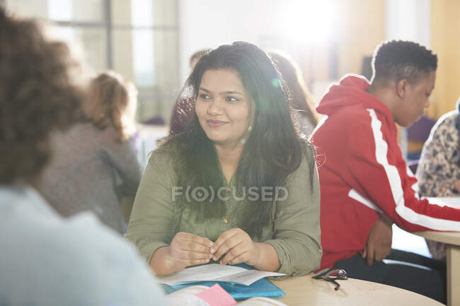 Sonriente joven estudiante universitaria que estudia con compañeros de clase - foto de stock