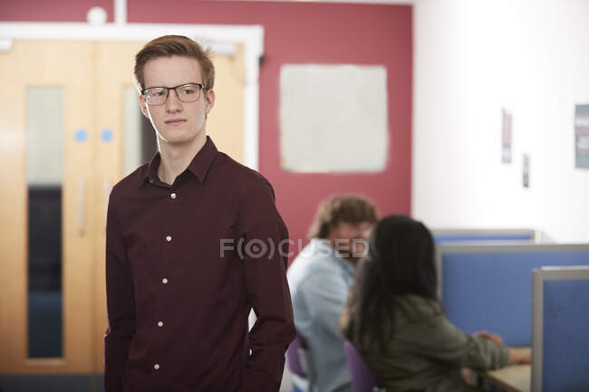 Retrato confiante jovem estudante universitário na biblioteca — Fotografia de Stock