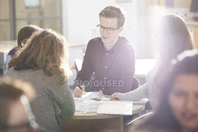 Jovens estudantes universitários estudando juntos em sala de aula ensolarada — Fotografia de Stock