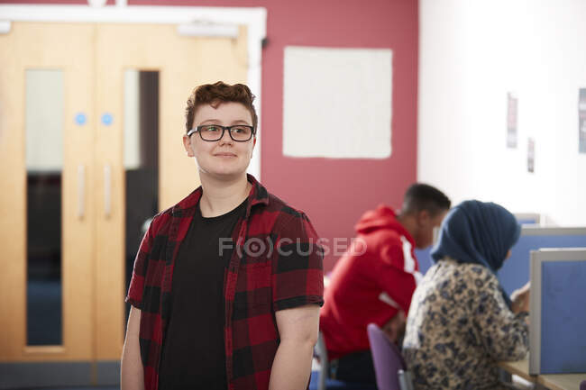 Portrait confiant ambitieux jeune étudiant du collège masculin à la bibliothèque — Photo de stock