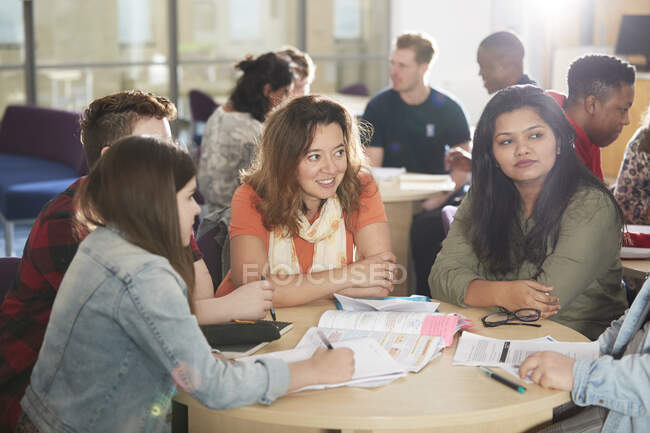 Студенты колледжа учатся и разговаривают за библиотечным столом — стоковое фото
