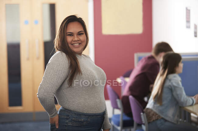 Portrait confident happy young female college student in library — Stock Photo