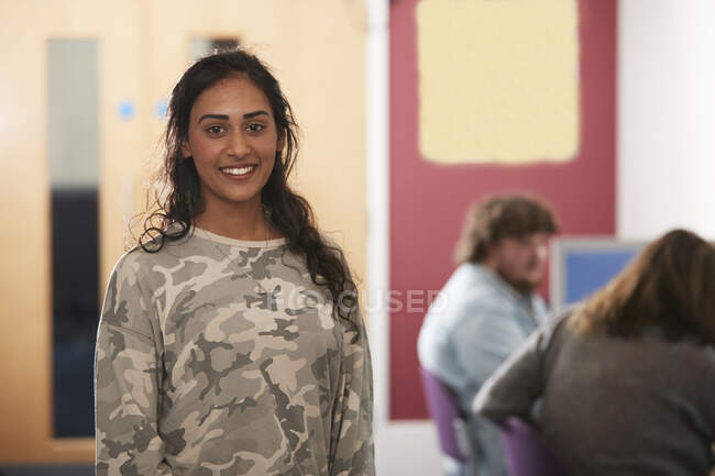 Portrait confident young female college student in camouflage shirt — Stock Photo