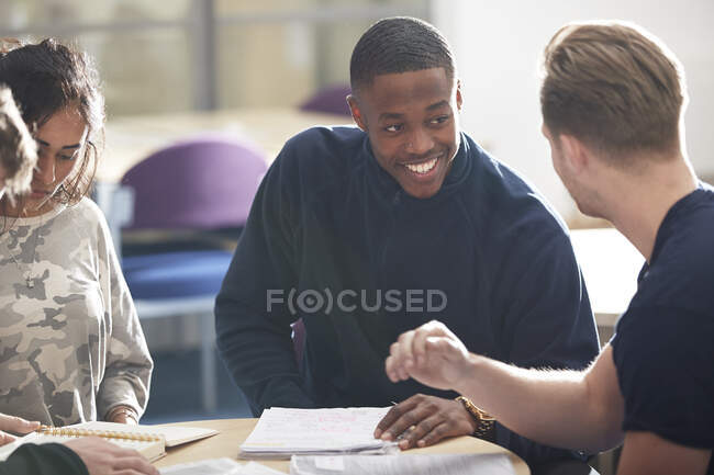 Happy young male college students studying and talking in classroom — Stock Photo