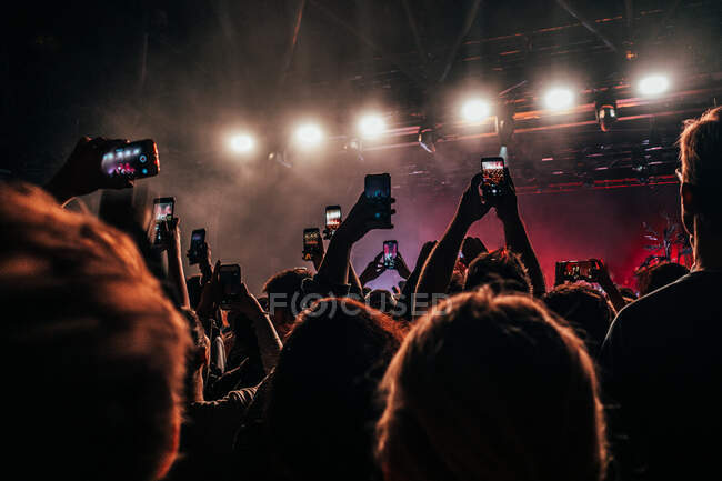 Multitud de teléfonos inteligentes filmando concierto de música - foto de stock