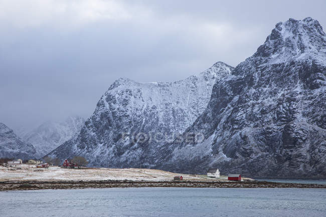 Montañas cubiertas de nieve sobre la aldea Flakstadpollen Lofoten Noruega - foto de stock