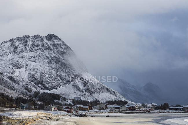 Montanha coberta de neve acima da aldeia remota Ramberg Lofoten Noruega — Fotografia de Stock