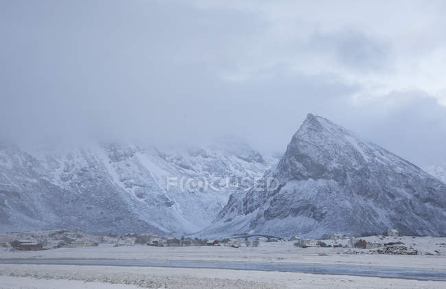 Majestuosas montañas cubiertas de nieve sobre el pueblo Ramberg Lofoten Noruega - foto de stock