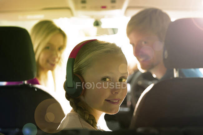 Portrait smiling girl with headphones riding in back seat of car — Stock Photo