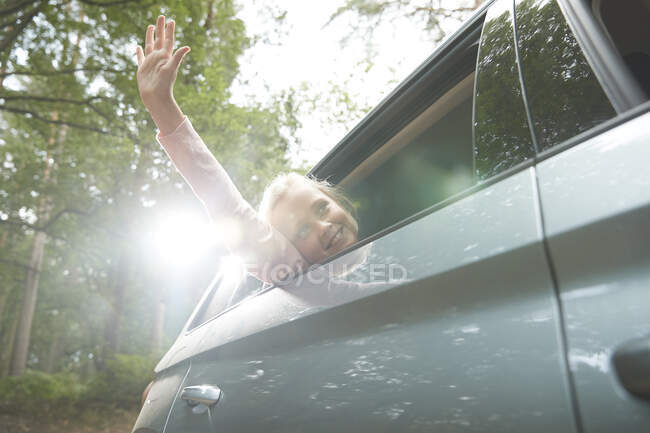 Menina despreocupada com braço para fora ensolarado janela do carro — Fotografia de Stock