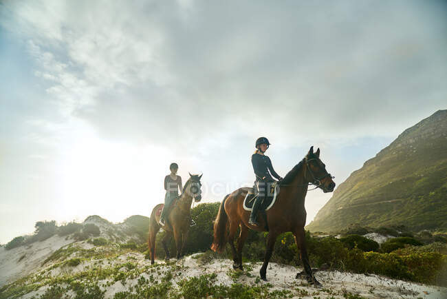 Giovani donne a cavallo sulla spiaggia soleggiata — Foto stock
