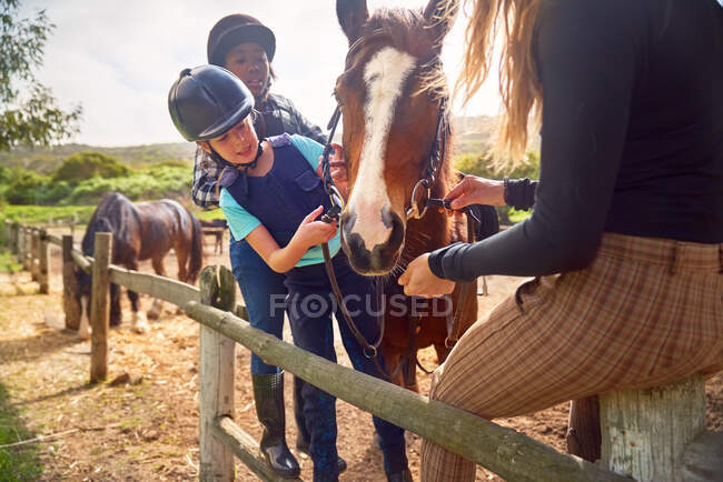 Mulher e meninas preparando cavalo para passeios a cavalo na paddock — Fotografia de Stock