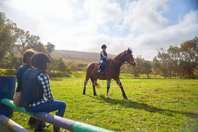 Menina cavalgando no ensolarado gramado paddock — Fotografia de Stock