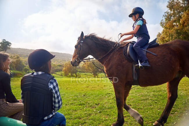 Girl learning horseback riding in rural grass paddock — Stock Photo
