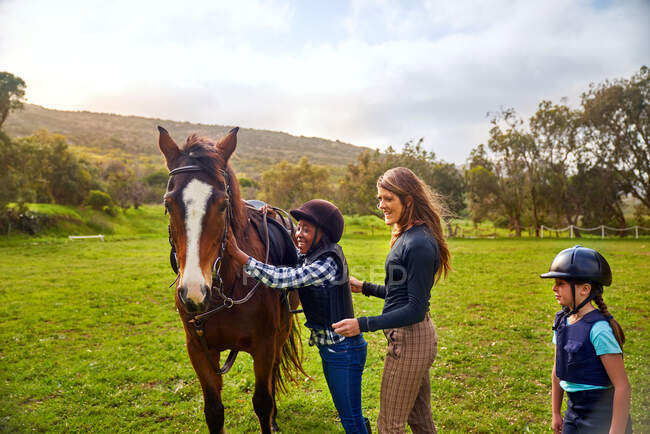 Happy girl petting horse during horseback riding lesson — Stock Photo