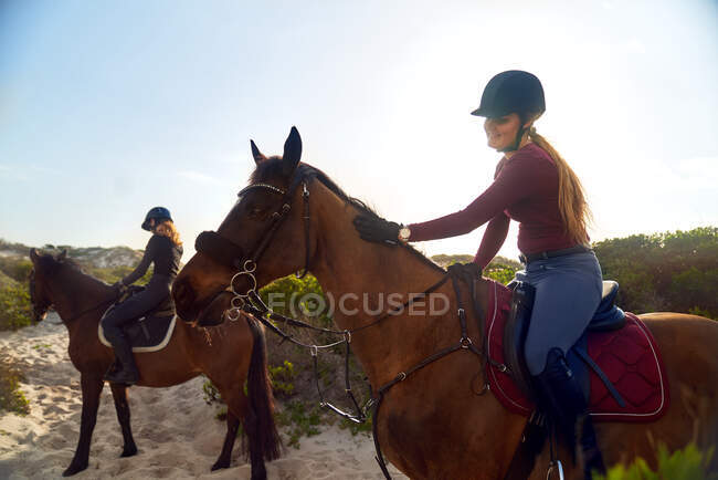 Jovens mulheres cavalgando na praia — Fotografia de Stock