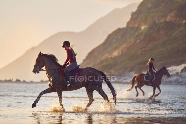 Молодые женщины катаются на лошадях в океане — стоковое фото