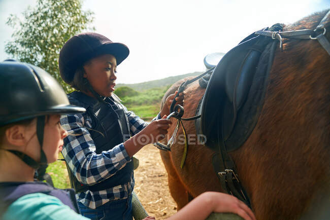 Niñas ajustando estribos para montar a caballo - foto de stock