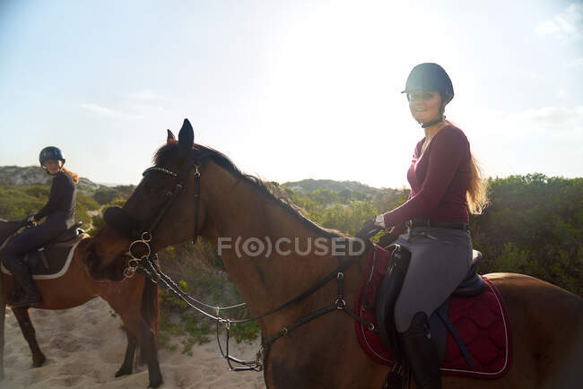Retrato mujer joven feliz montar a caballo en la playa soleada - foto de stock