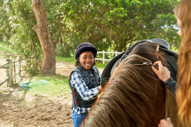 Portrait confident girl preparing saddle for horseback riding — Stock Photo