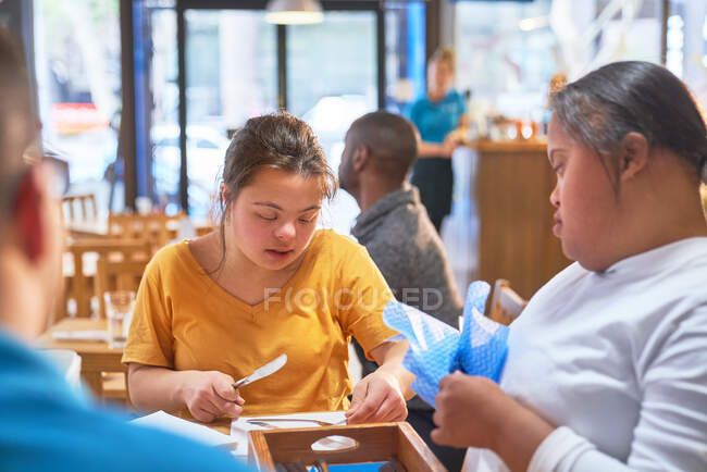 Young women with Down Syndrome cleaning silverware in cafe — Stock Photo