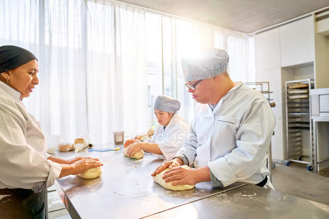 Chef teaching students with Down Syndrome how to bake in kitchen — Stock Photo