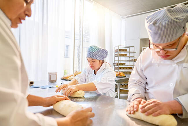 Estudantes com Síndrome de Down aprendendo a assar pão na cozinha — Fotografia de Stock