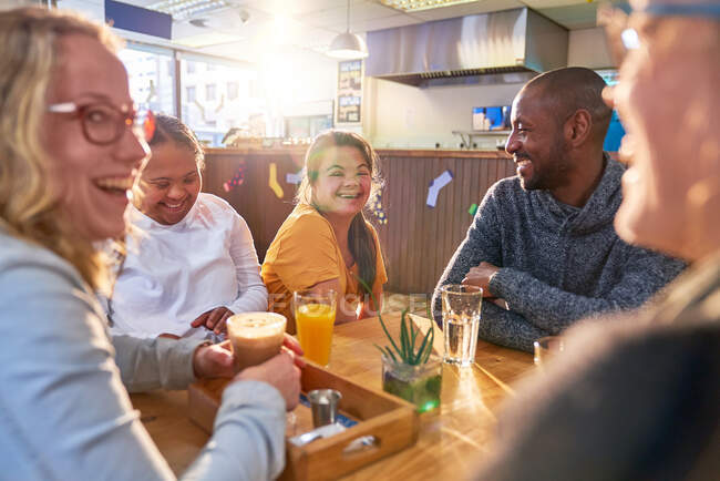 Молодые женщины с синдромом Дауна смеются с друзьями в кафе — стоковое фото
