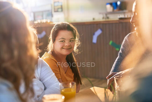 Щаслива молода жінка з синдромом Дауна з друзями в кафе — стокове фото